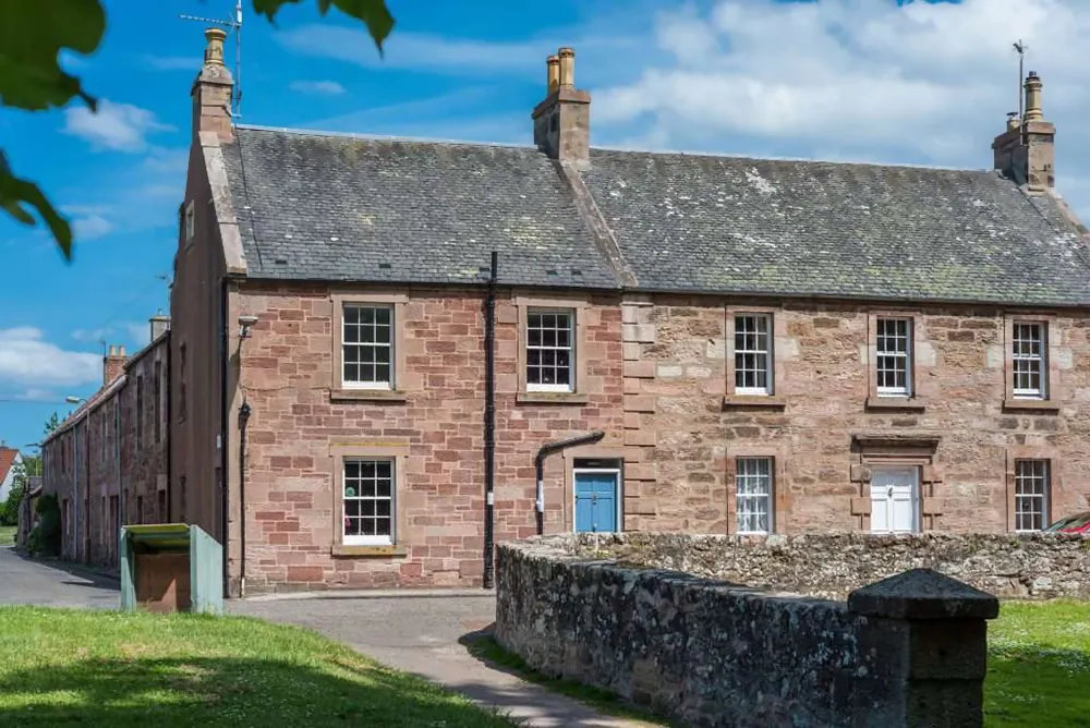Stone two-storey building with blue front door and sash windows