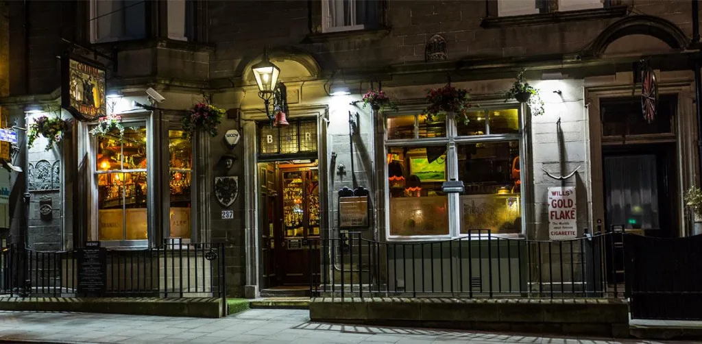 Night exterior view of Canny Man’s pub at 237 Morningside Road, Edinburgh, with its illuminated windows, hanging lanterns, and entrance.