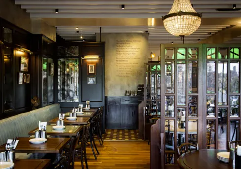Restaurant interior with wooden tables, banquette seating, crystal chandelier, and window views