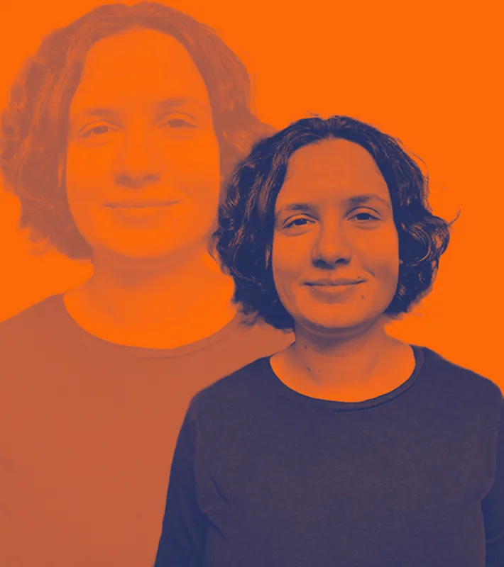 Woman with short curly hair in dark top against orange backdrop