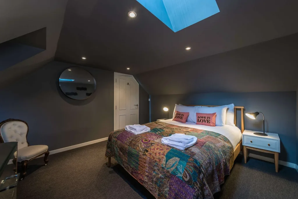 Bedroom with double bed, patchwork quilt, skylight, and bedside lamps
