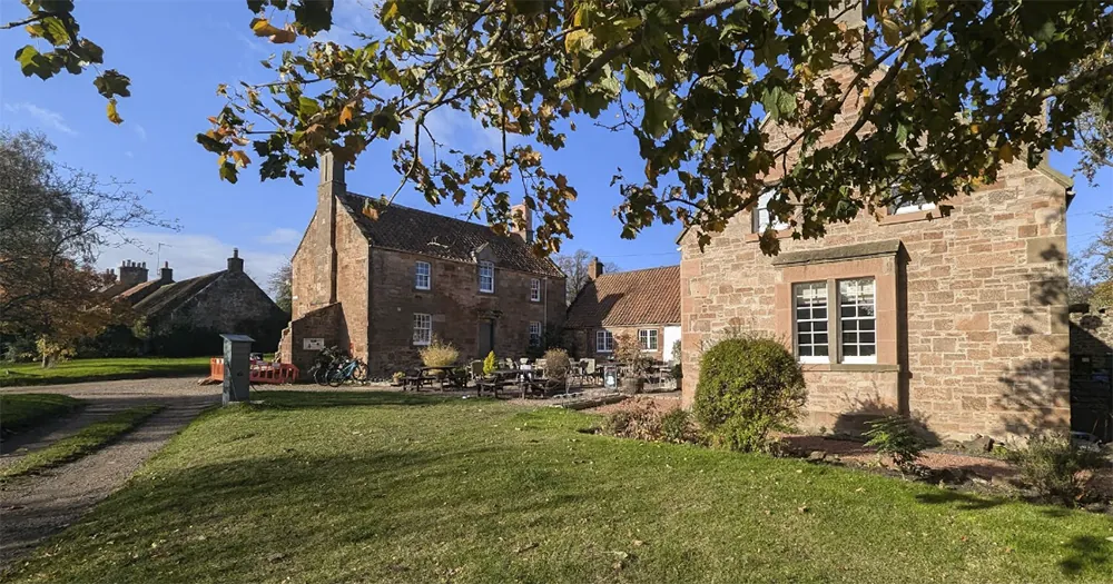 Historic stone cottages with outdoor seating in a scenic English village on a sunny day