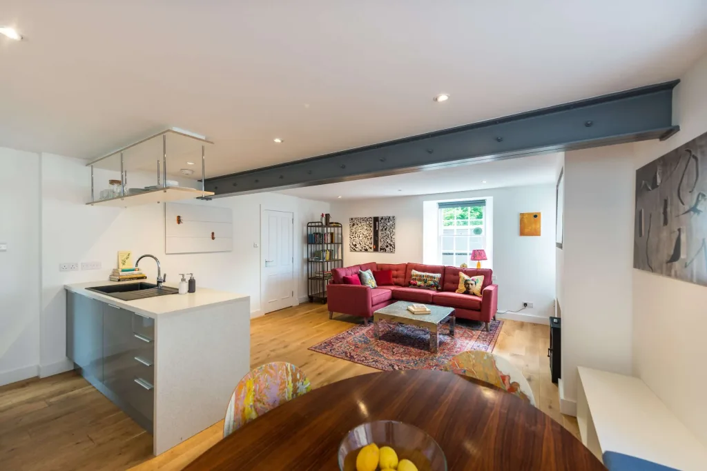 Open-plan kitchen and living room with red corner sofa, modern dining table, and decorative rug