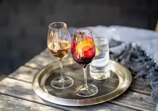 Red wine cocktail with orange slice, white wine and iced water on tray.