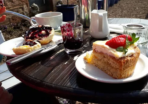 Homemade Victoria sponge cake with strawberry and cream tea with scones and jam outdoors