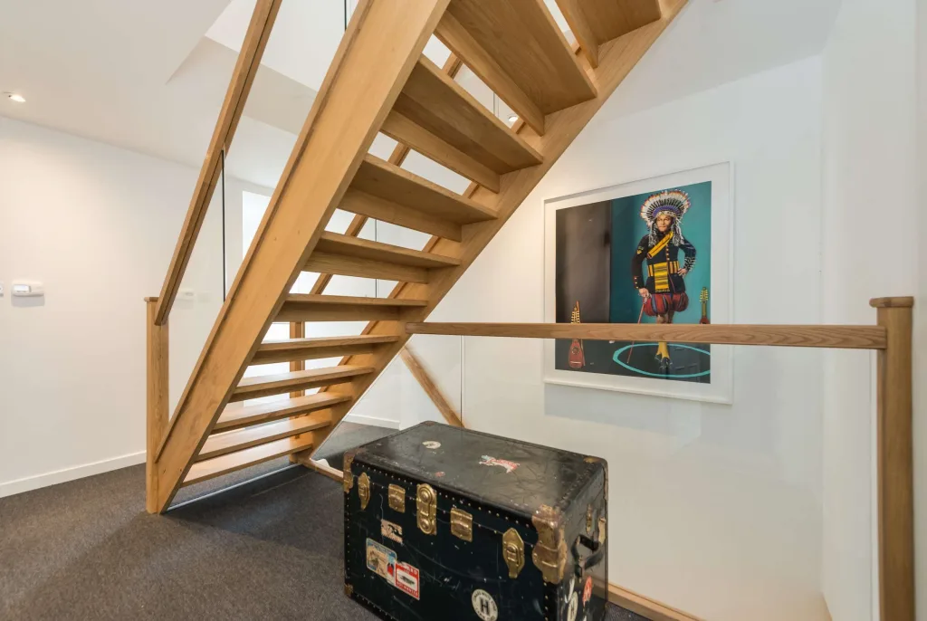 Wooden staircase with vintage trunk and framed artwork in cottage hallway